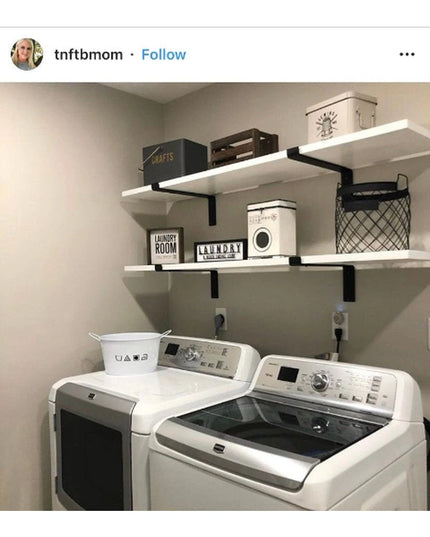 Black metal shelf brackets supporting white floating shelves above washer and dryer in organized laundry room with storage...