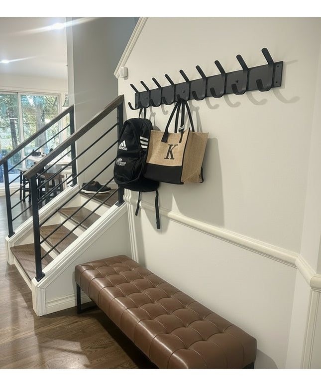 Riseform black metal wall mounted coat rack with multiple hooks installed in modern entryway with brown leather bench and ...