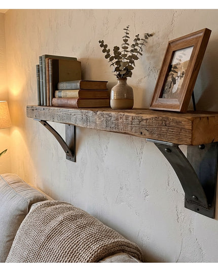 Rustic wooden floating shelf with black metal Industrial Farm Co Moravia 4" brackets displaying books, vase with eucalyptu...