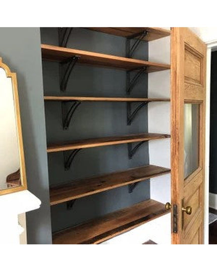 Black metal Niagara bracket supports holding wooden shelves in rustic farmhouse pantry with dark blue painted walls