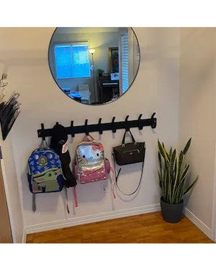 Black wall-mounted Fairmount Style Coat Rack by Industrial Farm Co with multiple hooks holding backpacks and bags in entryway