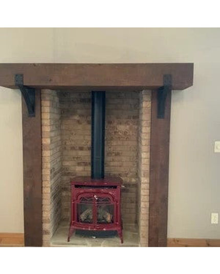 Heavy duty black steel Spafford mantel brackets with rivets supporting rustic wood beam mantel over brick fireplace with r...