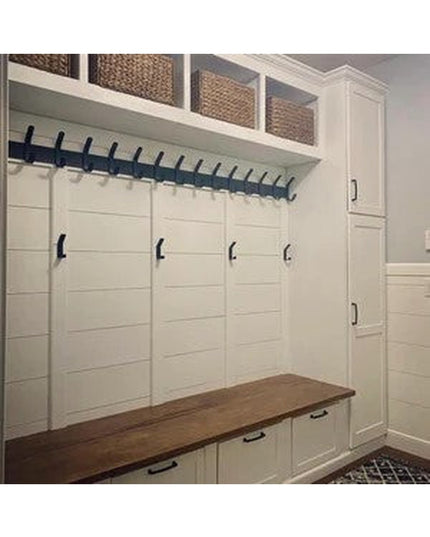 White built-in mudroom storage with Fairmount Style black metal coat rack, wooden bench, cubbies and wicker baskets by Ind...