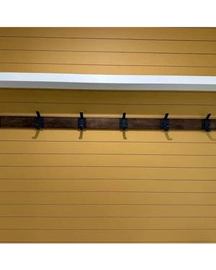 Five black metal wall hooks mounted on wooden rail against yellow wood siding - The Elizabeth Wall Hook by Industrial Farm Co