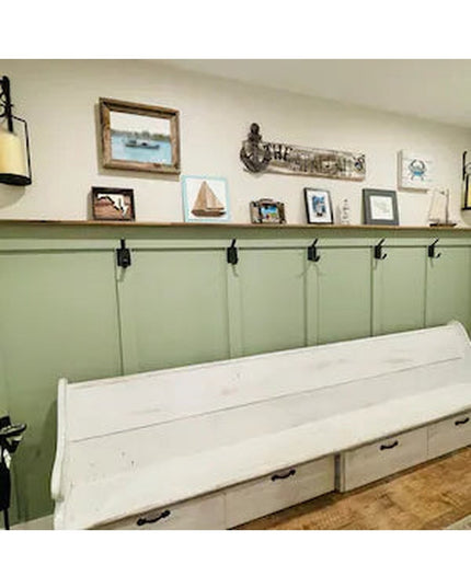 Black iron Elizabeth wall hooks mounted on sage green wainscoting with white storage bench and nautical decor by Industria...