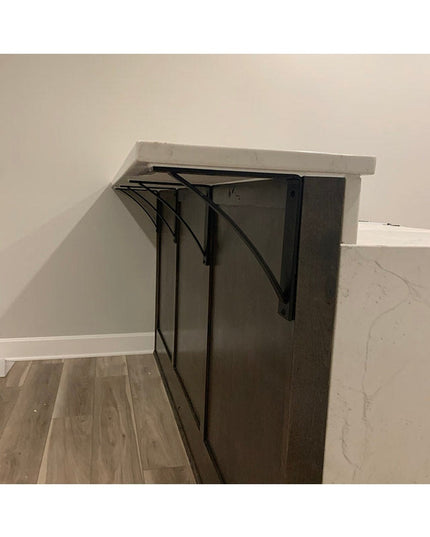 Heavy duty black steel Pops 2" industrial shelf brackets with curved support bars mounted under white wooden shelf against...