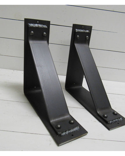 Two black metal Ithaca Rustic Bracket Supports by Industrial Farm Co with welded steel construction and mounting holes on ...
