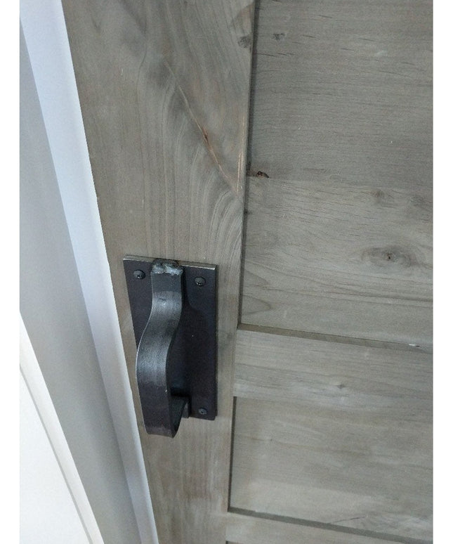 Black metal Lockport Pull door handle mounted on weathered gray wood barn door by Industrial Farm Co