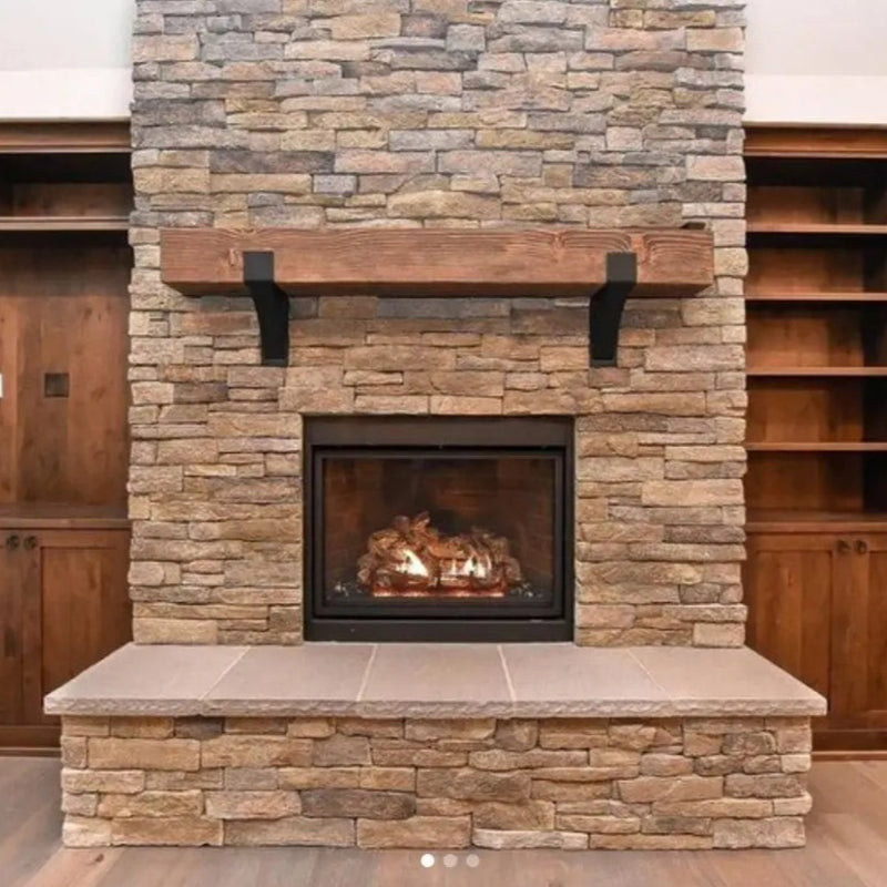 Reclaimed wood shelf mounted on white shiplap wall with black Kudlick farmhouse mantel brackets, styled with an arched mirror, candles, and trailing greenery