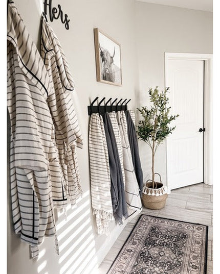 Black metal wall-mounted Fairmount Style Coat Rack by Industrial Farm Co holding striped towels and clothing in modern far...