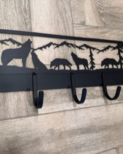 Black metal wolf silhouette coat rack with mountain wilderness scene, featuring 6 hooks mounted on light wood wall by Indu...