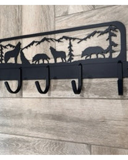 Black metal wall-mounted coat rack with wolf and mountain wilderness scene silhouette design featuring 5 hooks on wood bac...